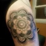 Black and gray floral mandala tattoo on an upper arm