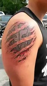 Close-up of a colorful tattoo on an upper arm, showing a red and black abstract design