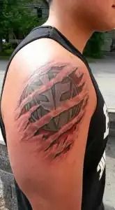Close-up of a person’s upper arm with a large black and red abstract tattoo.