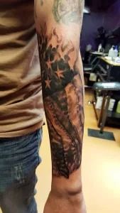 Close-up of a tattooed forearm with a dark star and tribal-style design.