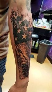 Leg tattoo on a lower leg with stars and ornate black-and-gray designs, shown indoors.