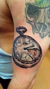 Tattoo of a pocket watch on an upper arm, with a skull tattoo above it.