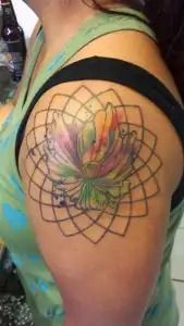 Colorful lotus tattoo with geometric linework on an upper arm