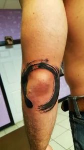 Close-up of a leg with a thick black circular ring or tattoo-like marking on the skin.