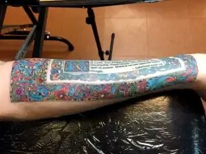 Forearm with a colorful patterned tattoo design, resting on a black surface.