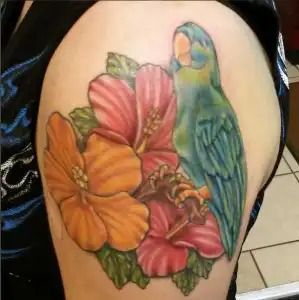 Colorful tattoo of flowers and a parrot on an upper arm