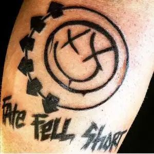 Black circular tattoo with arrows and “Take Fall Shout” text on skin