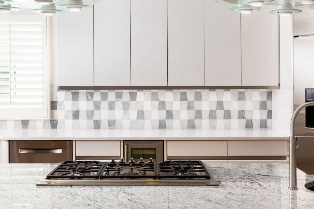 A kitchen with white cabinets and a stove top oven.