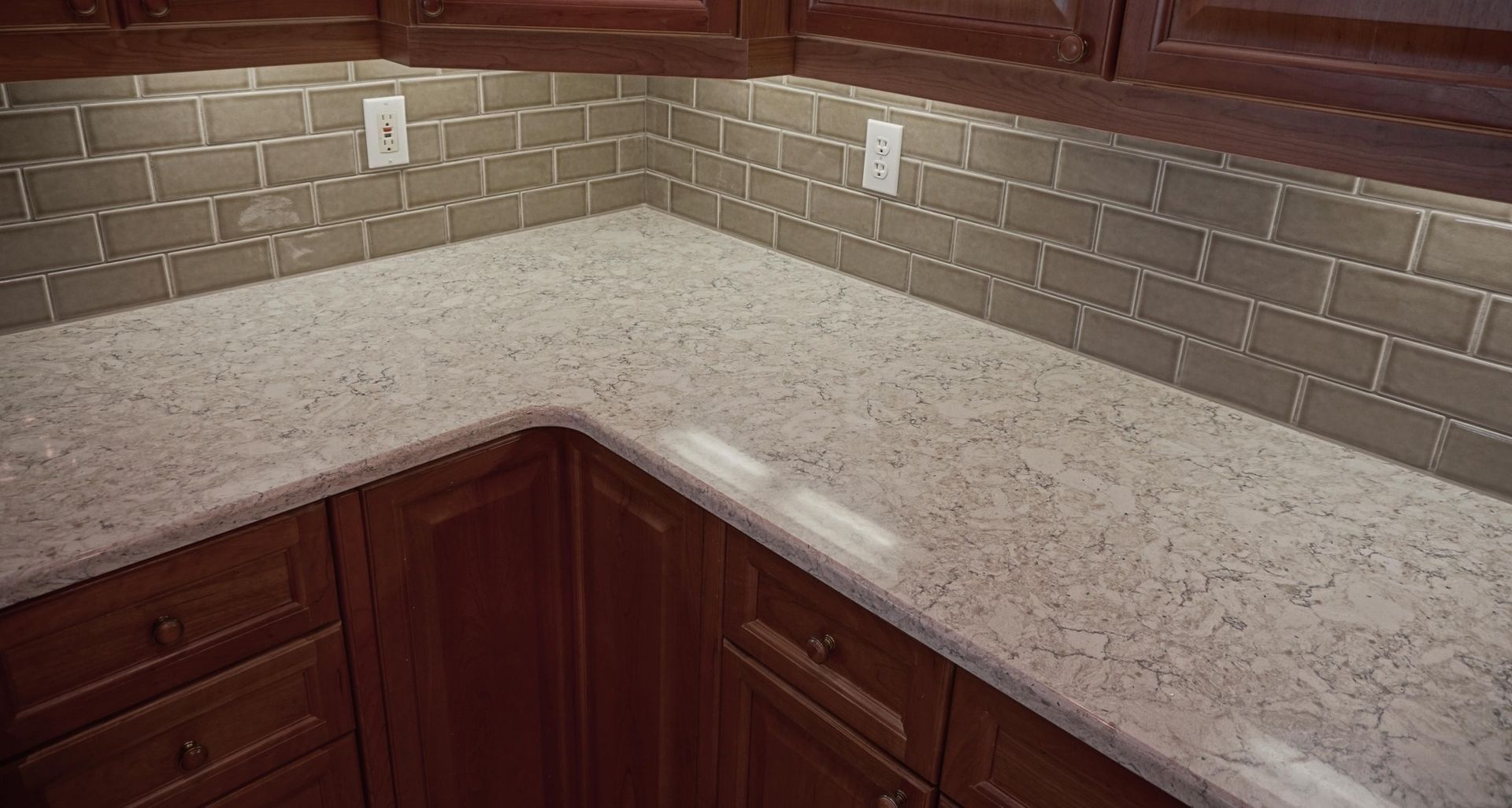 A kitchen with a granite counter top and brick tiles on the wall.