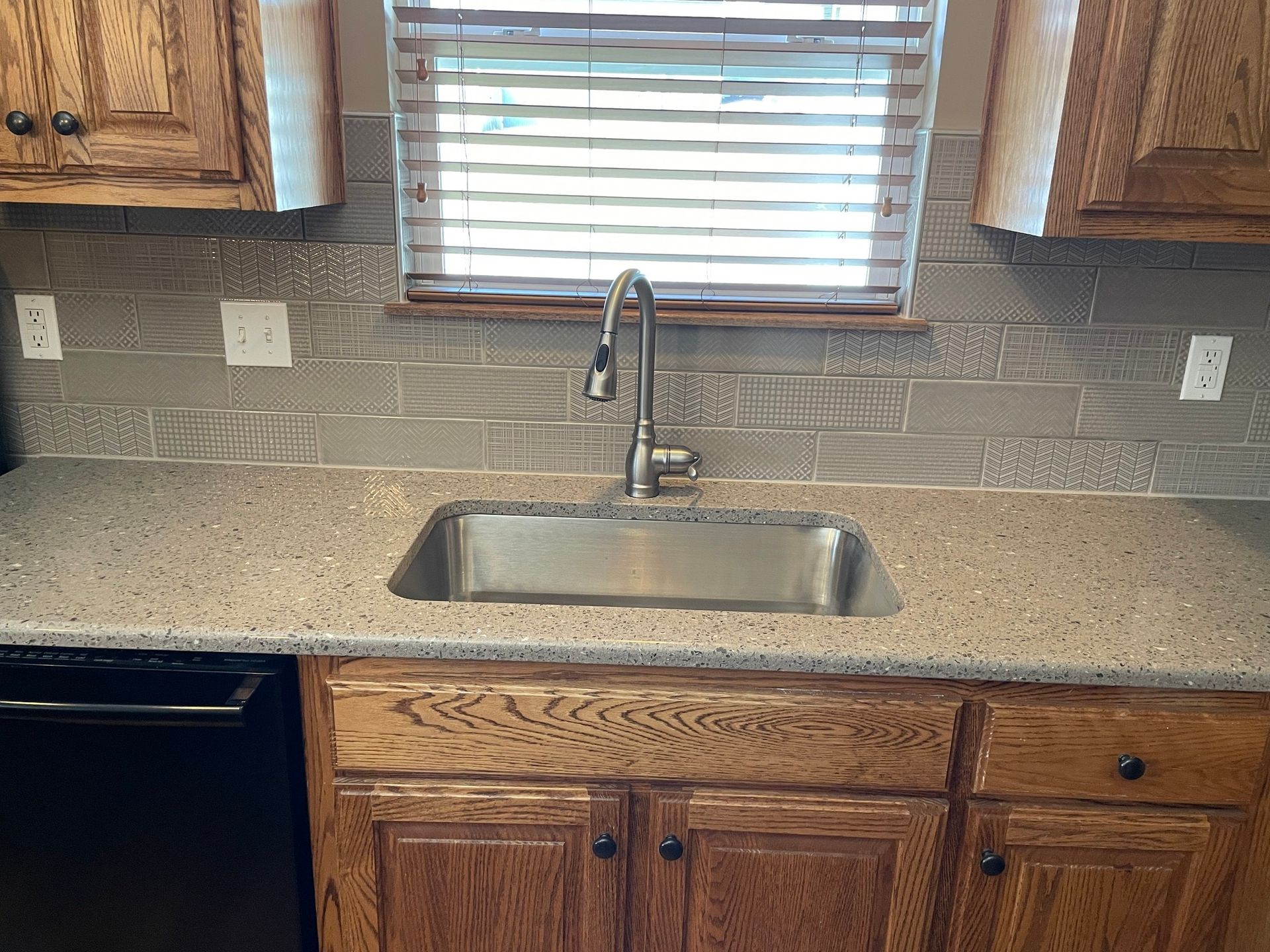 A kitchen with a stainless steel sink and a window.