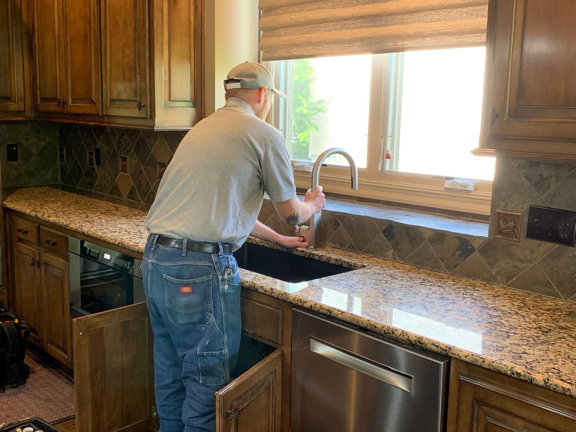 A man is cleaning a sink in a kitchen.