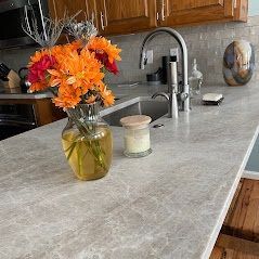 A vase of flowers is sitting on a kitchen counter next to a sink.