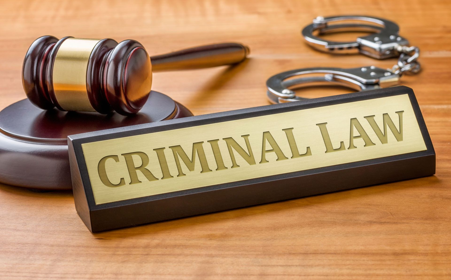 Criminal law plaque with gavel and handcuffs on a wooden desk