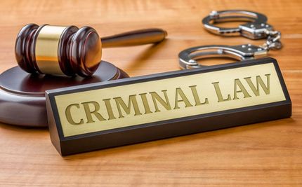 Criminal law plaque with gavel and handcuffs on a wooden desk