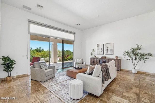 Bright modern living room with white sofas, large sliding glass doors, and patio views