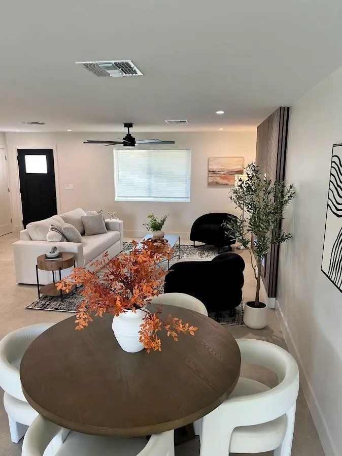 Bright open living room with sofa, round dining table, black chairs, and wall art.