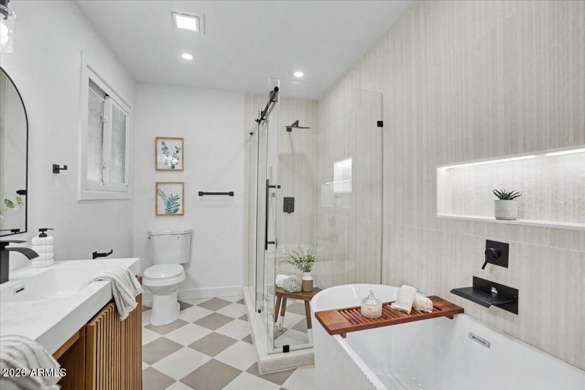 Bright white modern bathroom with freestanding tub, toilet, glass shower, and checkered floor.