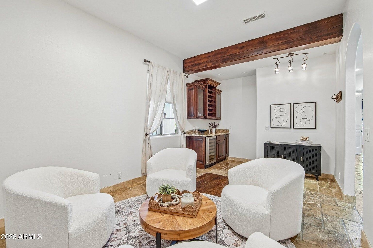 Bright living room with white chairs, round wooden table, fireplace, and large mirrors.