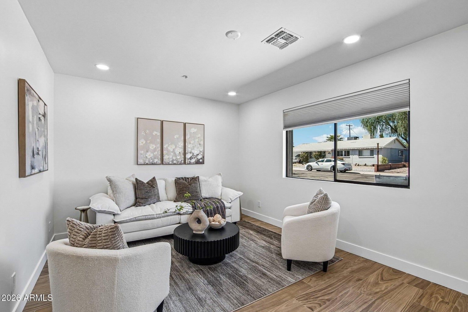 Bright modern living room with white sofa, chairs, gray rug, and large window view.