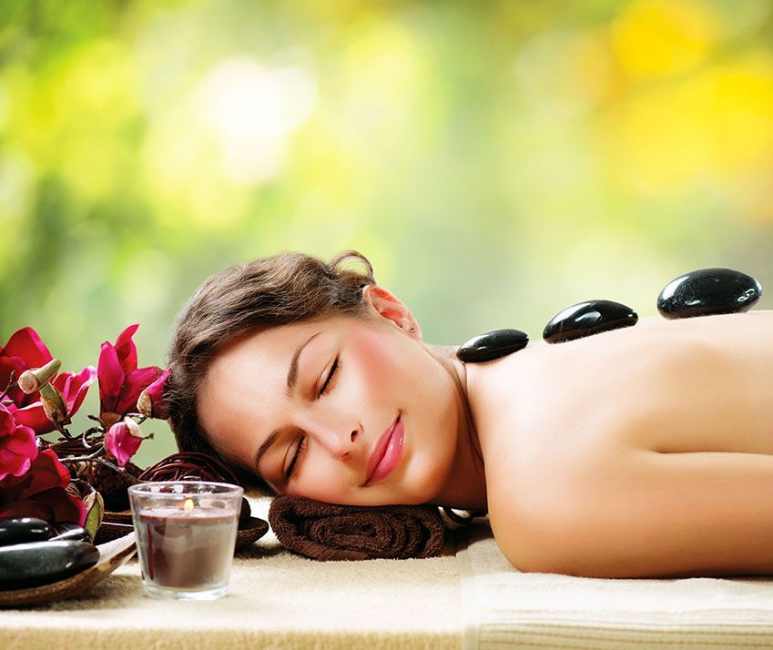 A woman is laying on a table with hot rocks on her back.