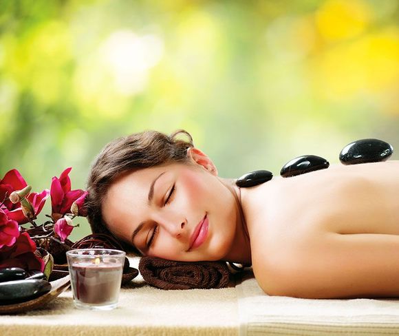 A woman is laying on a table with hot rocks on her back.
