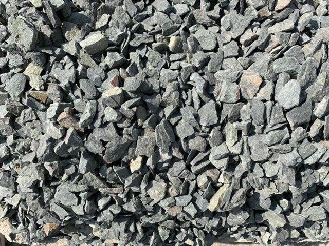 A pile of black gravel is sitting on top of a wooden table.