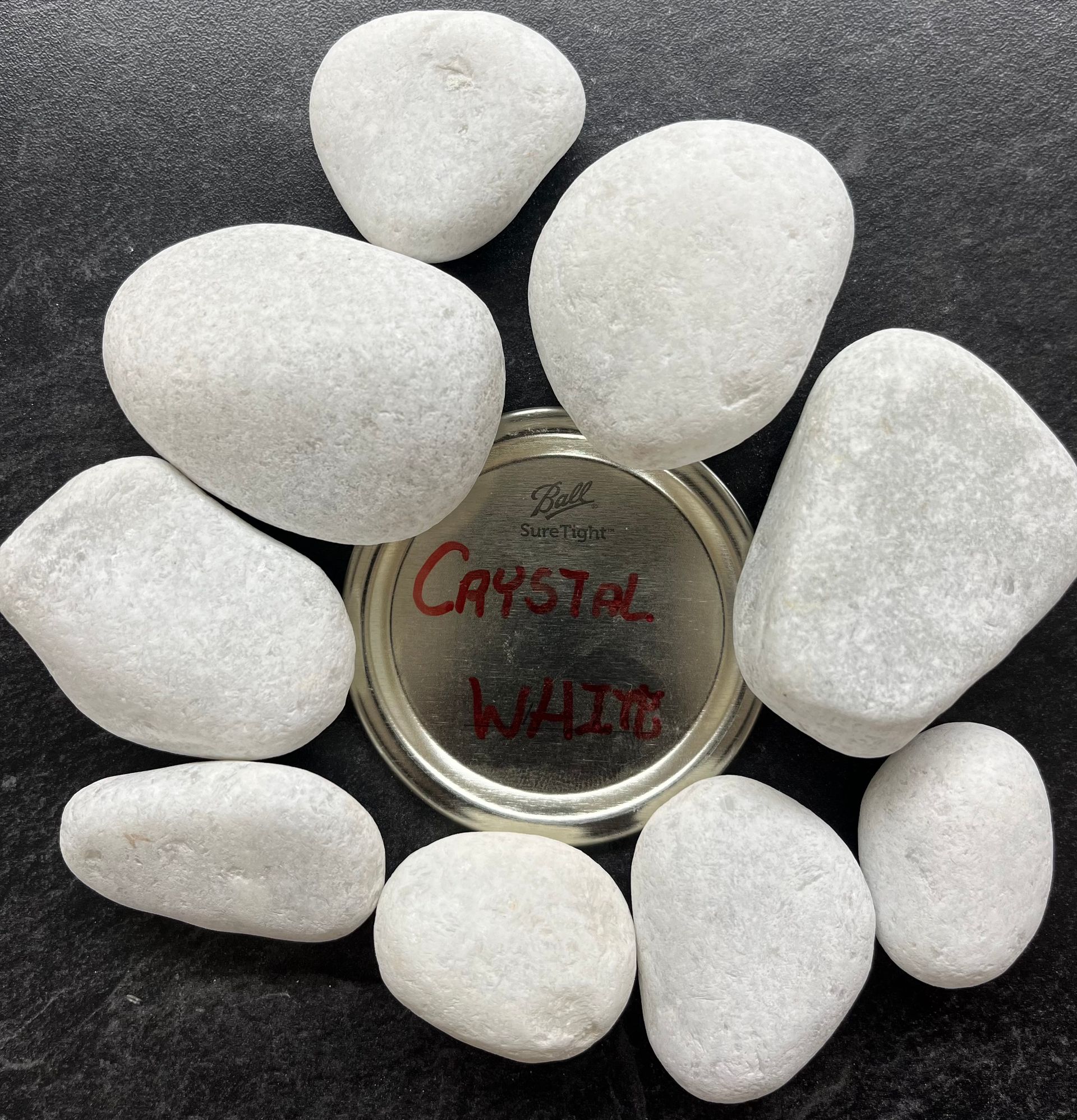A bunch of white rocks are sitting around a metal container that says crystal white