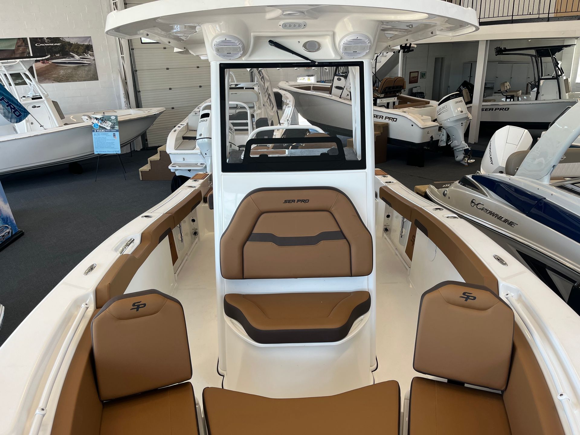 Interior view of a white boat with brown seating. It is in a showroom.