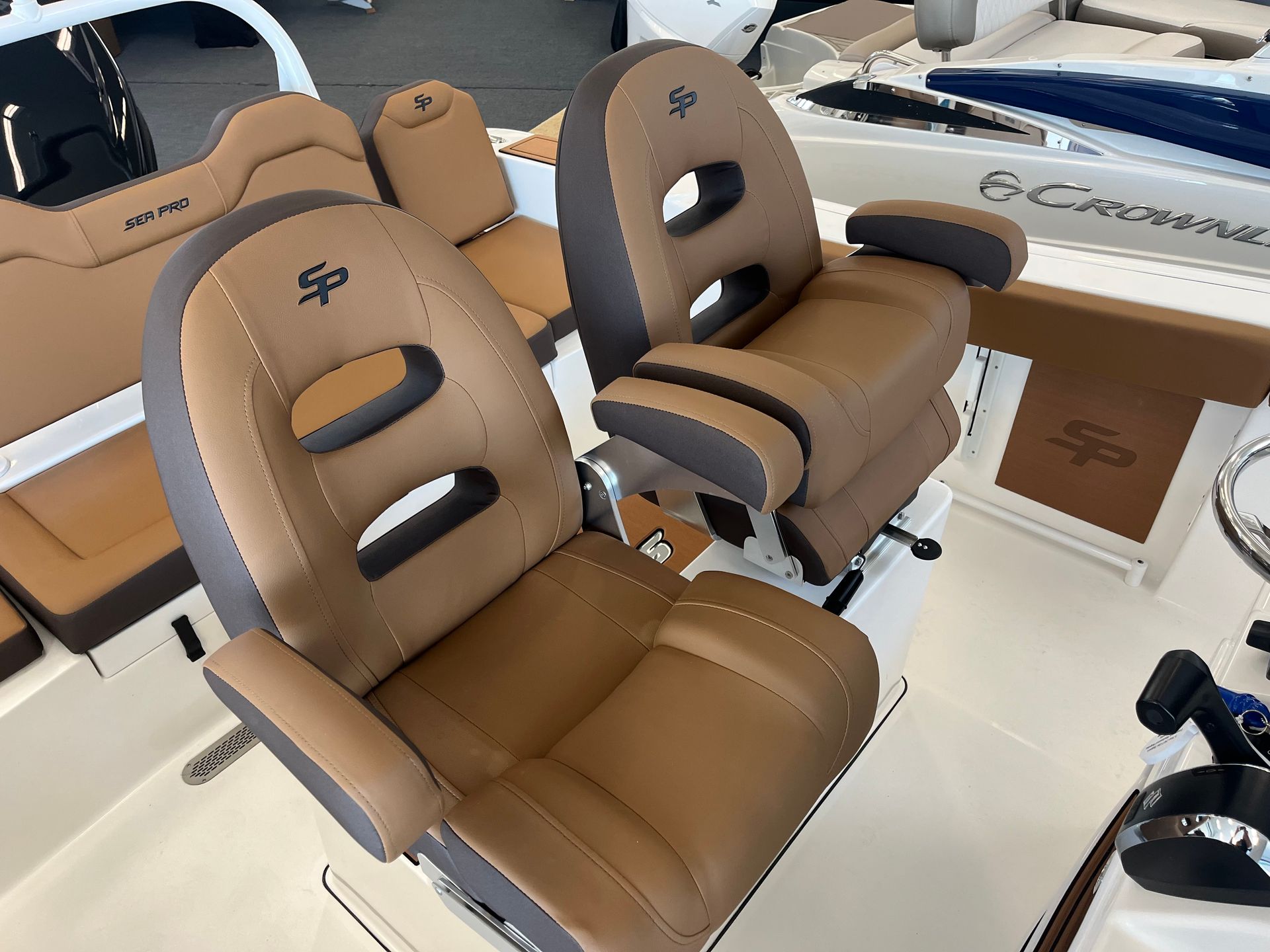 Two brown and gray boat captain's chairs with armrests, facing the camera, in a boat.