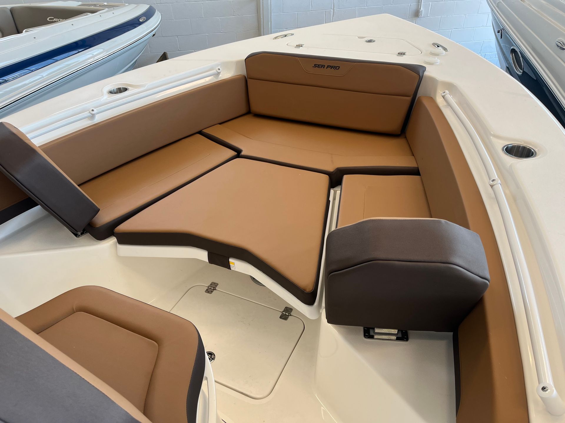Boat's front seating area with tan and brown cushions, white boat interior.