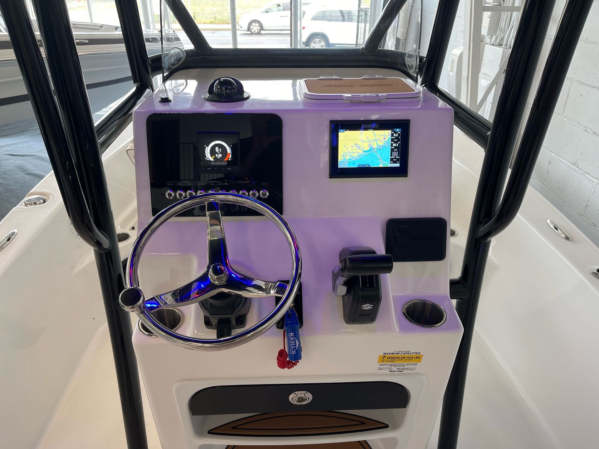 The cockpit of a boat with a steering wheel and a monitor.
