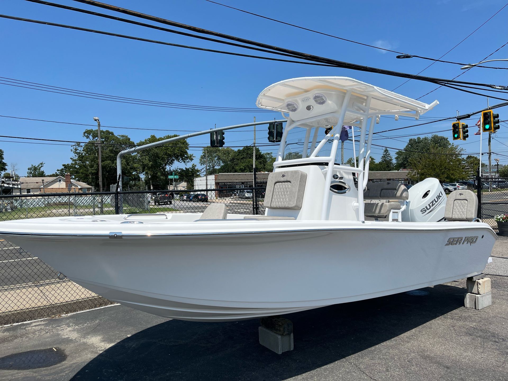 A white boat with a canopy is parked on the side of the road.