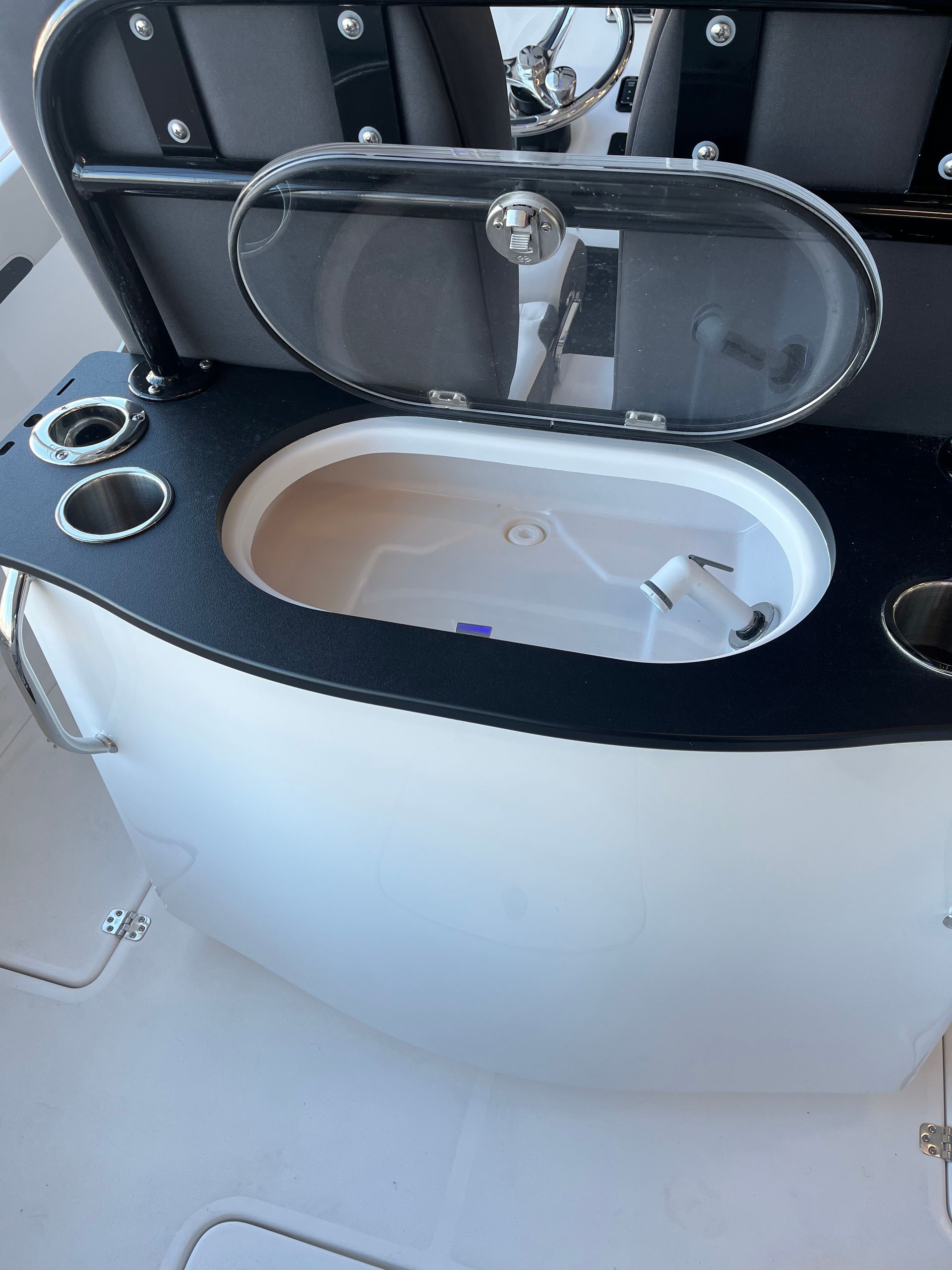 Boat with built in cooler, cup holders, and hinged lid. Black countertop, white exterior.