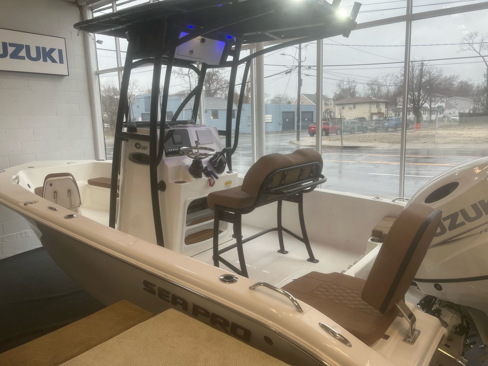 A white boat with a brown seat is sitting in a showroom.