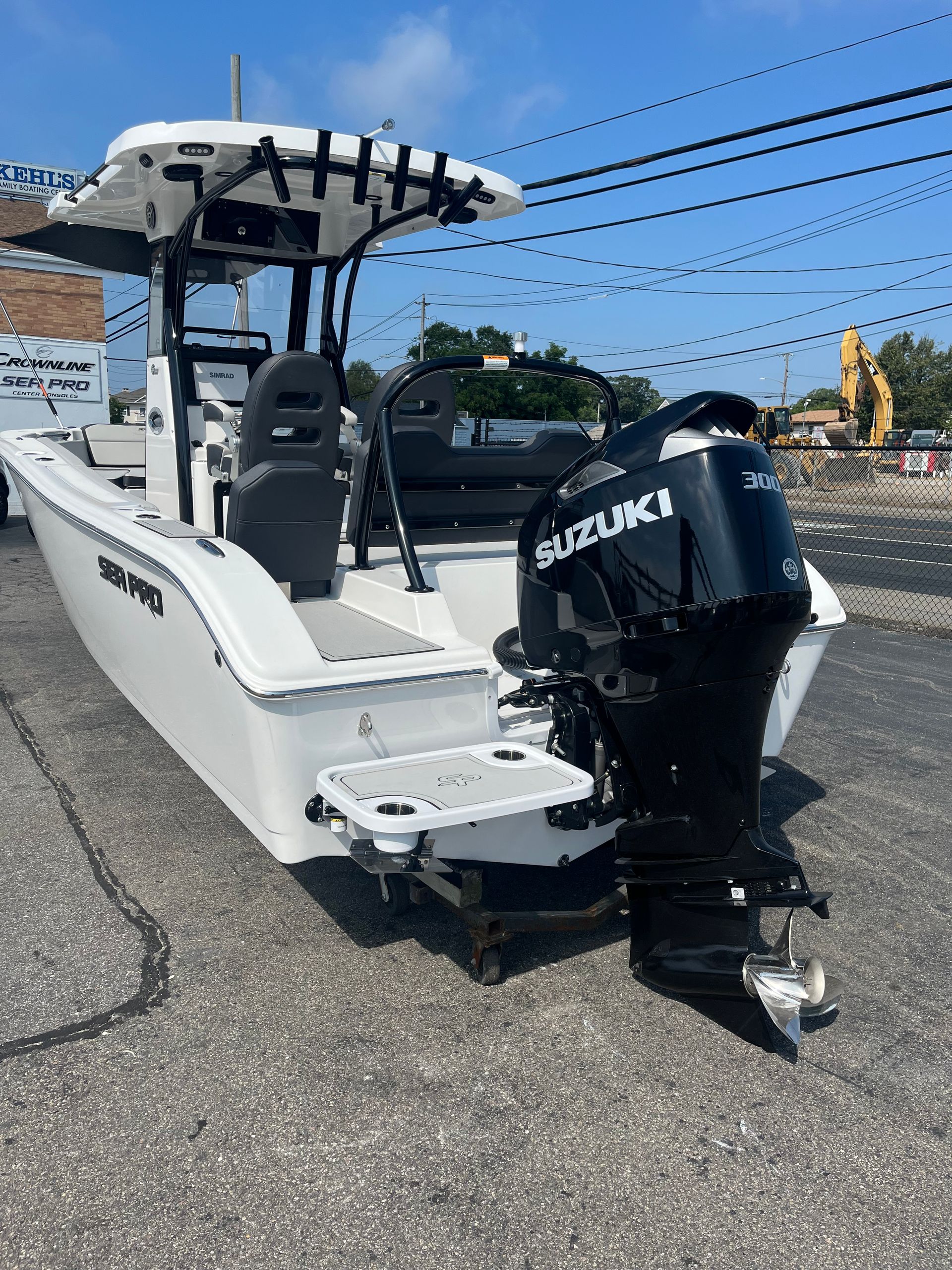 White motorboat with black Suzuki engine; parked on pavement, blue sky background.