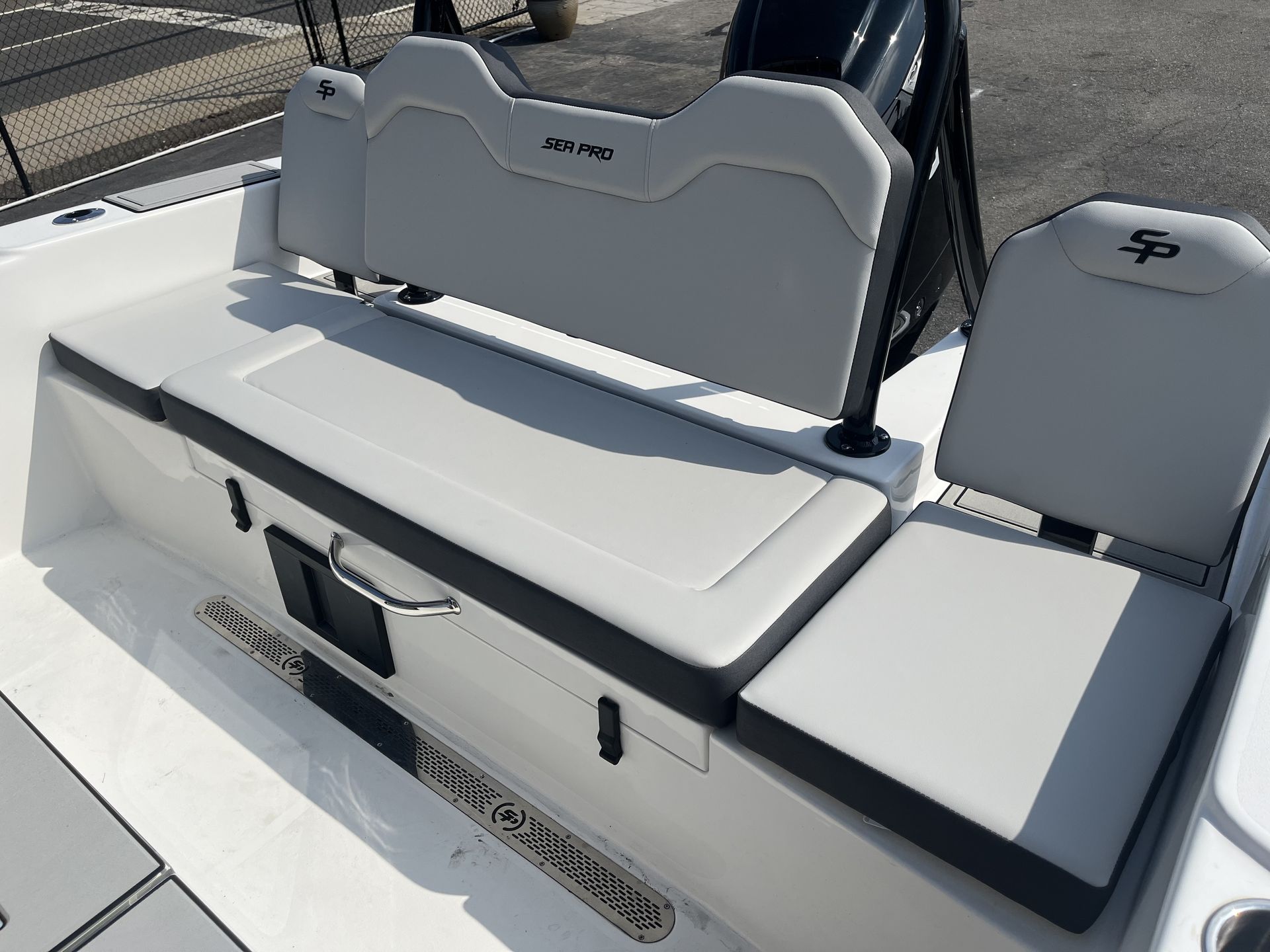 A boat's white and gray cushioned seating area with backrests, including a bench and individual seat.