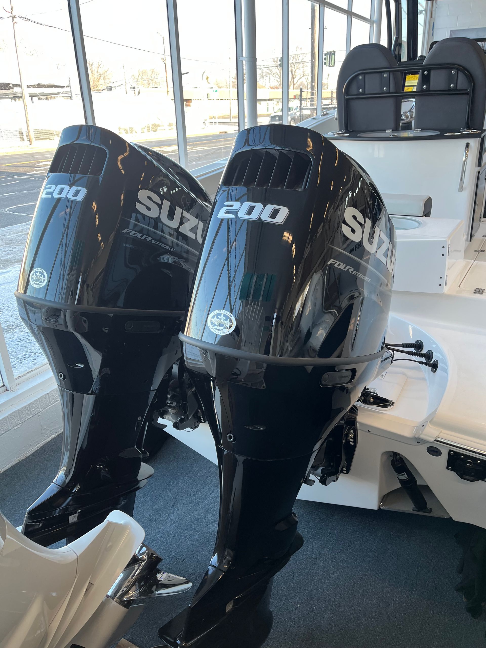Two black Suzuki 200 outboard motors attached to a white boat.