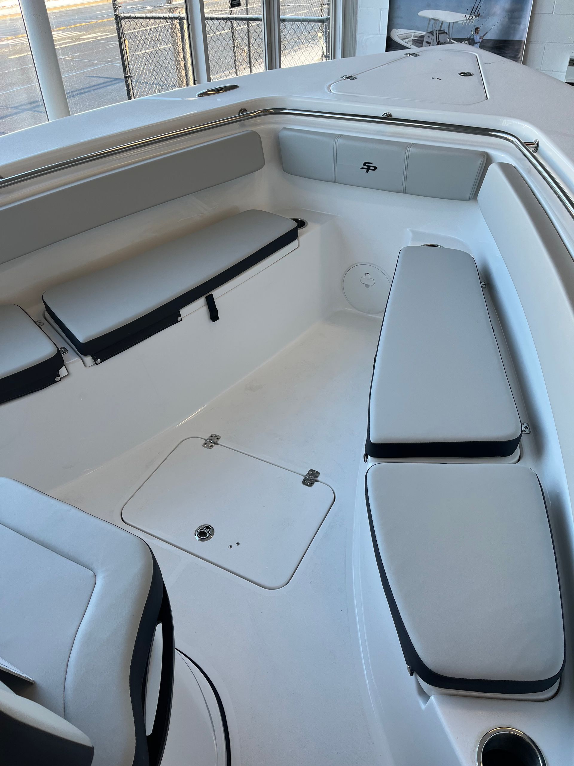 Interior of a white boat with gray seating and storage compartments.