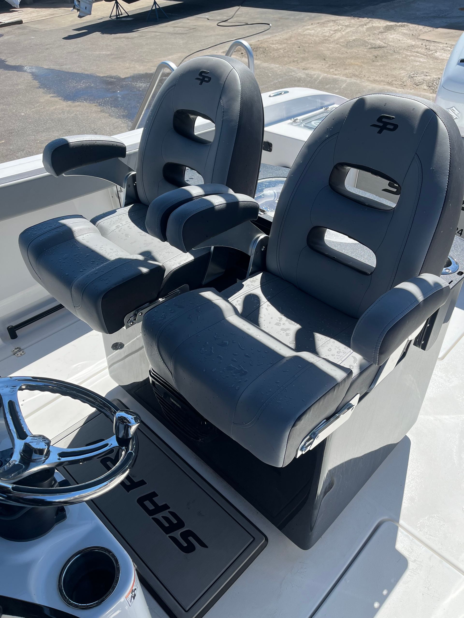 Two grey and black captain’s chairs on a Sea Pro boat, with a steering wheel and cup holder visible in the foreground.