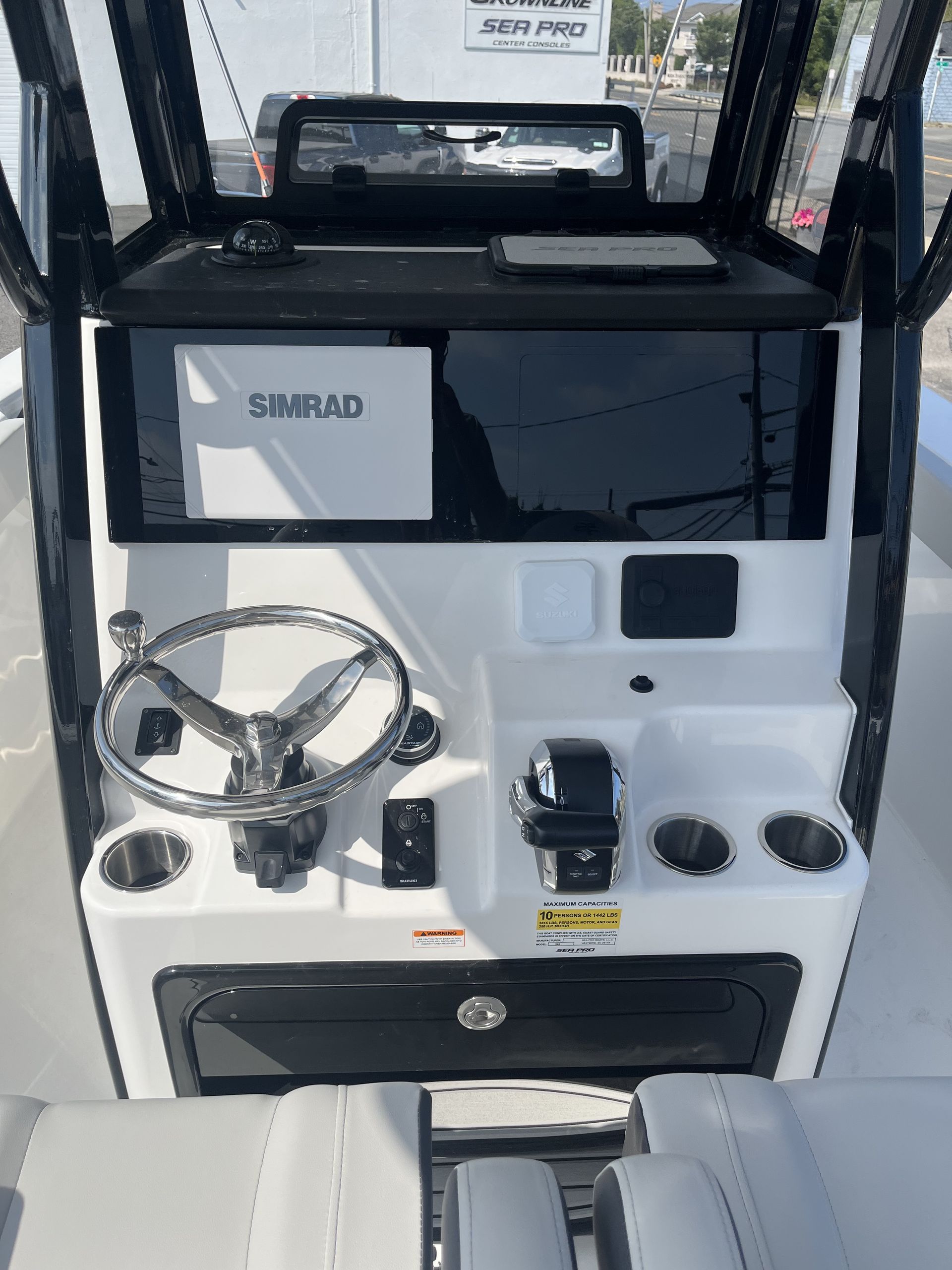 Boat console with steering wheel, Simrad display, and cup holders.