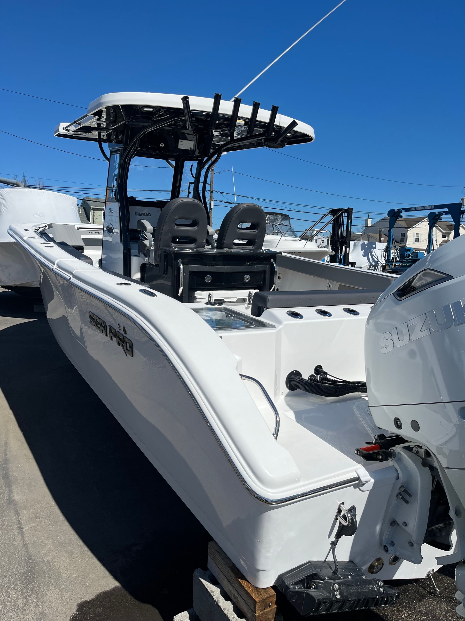 A white center-console motorboat parked on a lot under a clear blue sky.