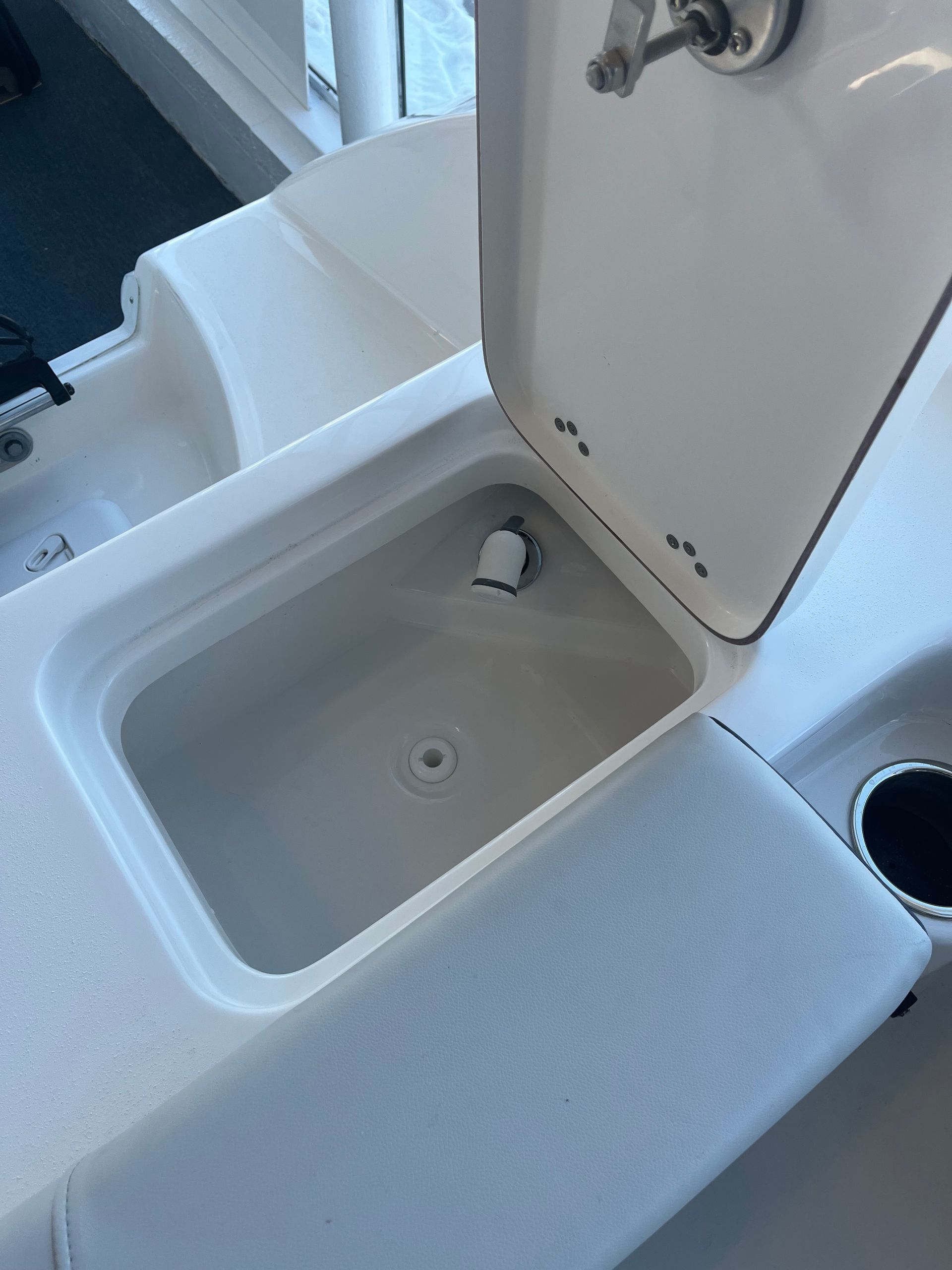 A white sink with the lid open on a boat