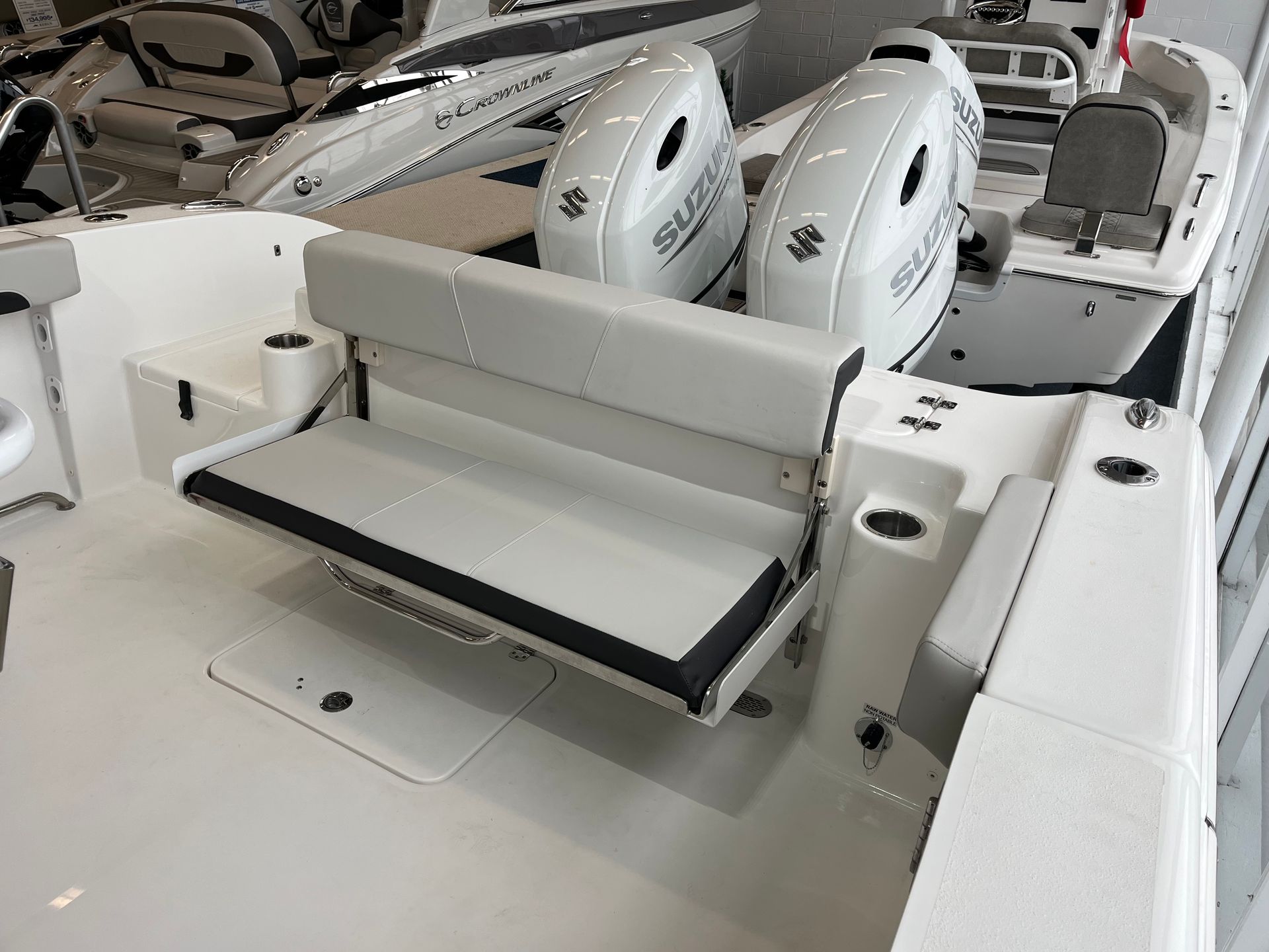 A white boat with two engines is sitting in a showroom.