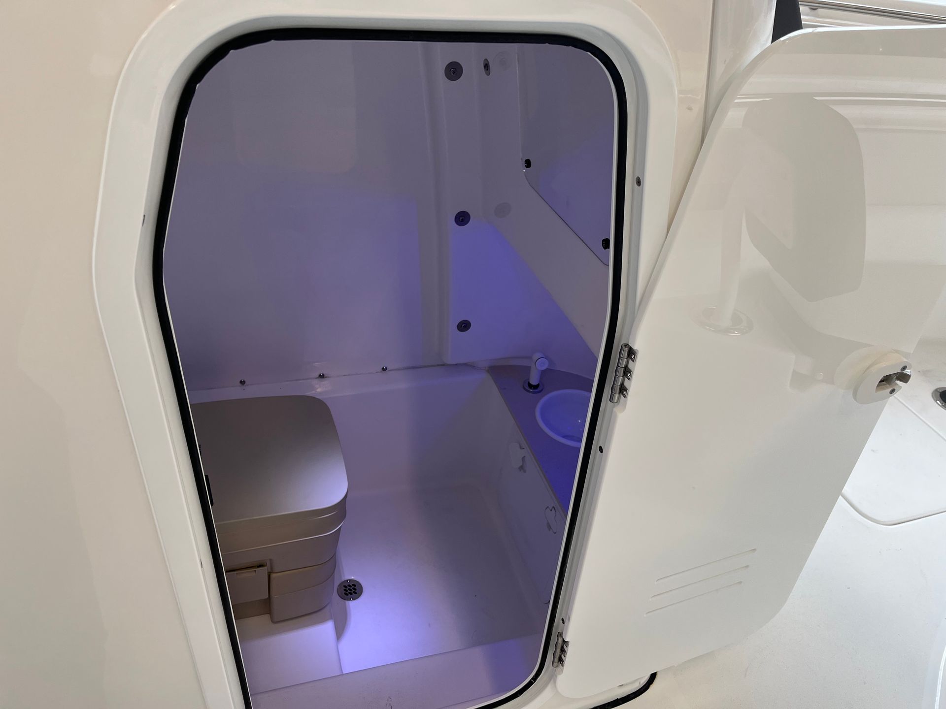 A bathroom on a boat with a toilet and a door open.