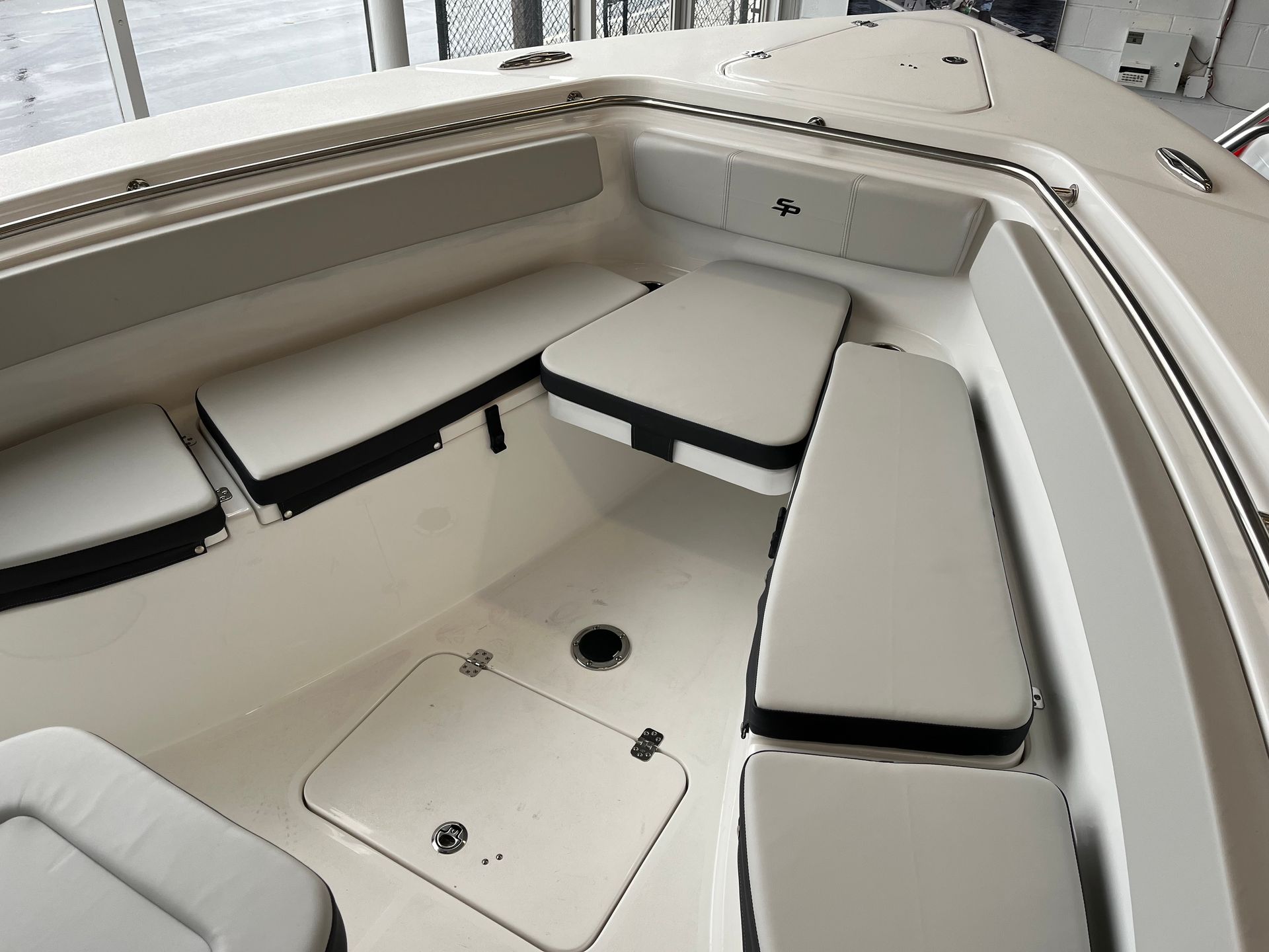 The inside of a boat with white seats and a cooler.