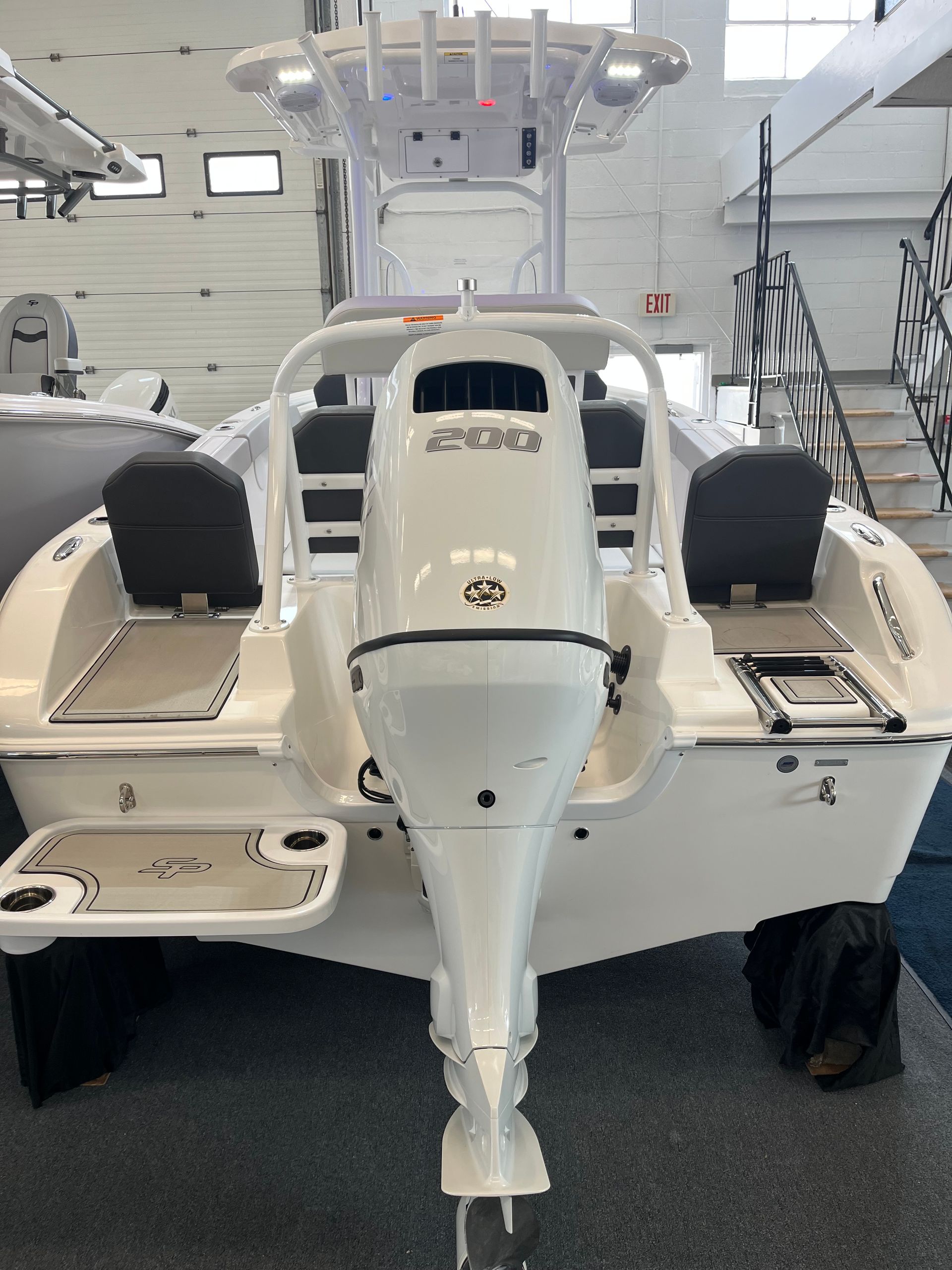 A white boat with a mercury outboard motor is sitting in a showroom.
