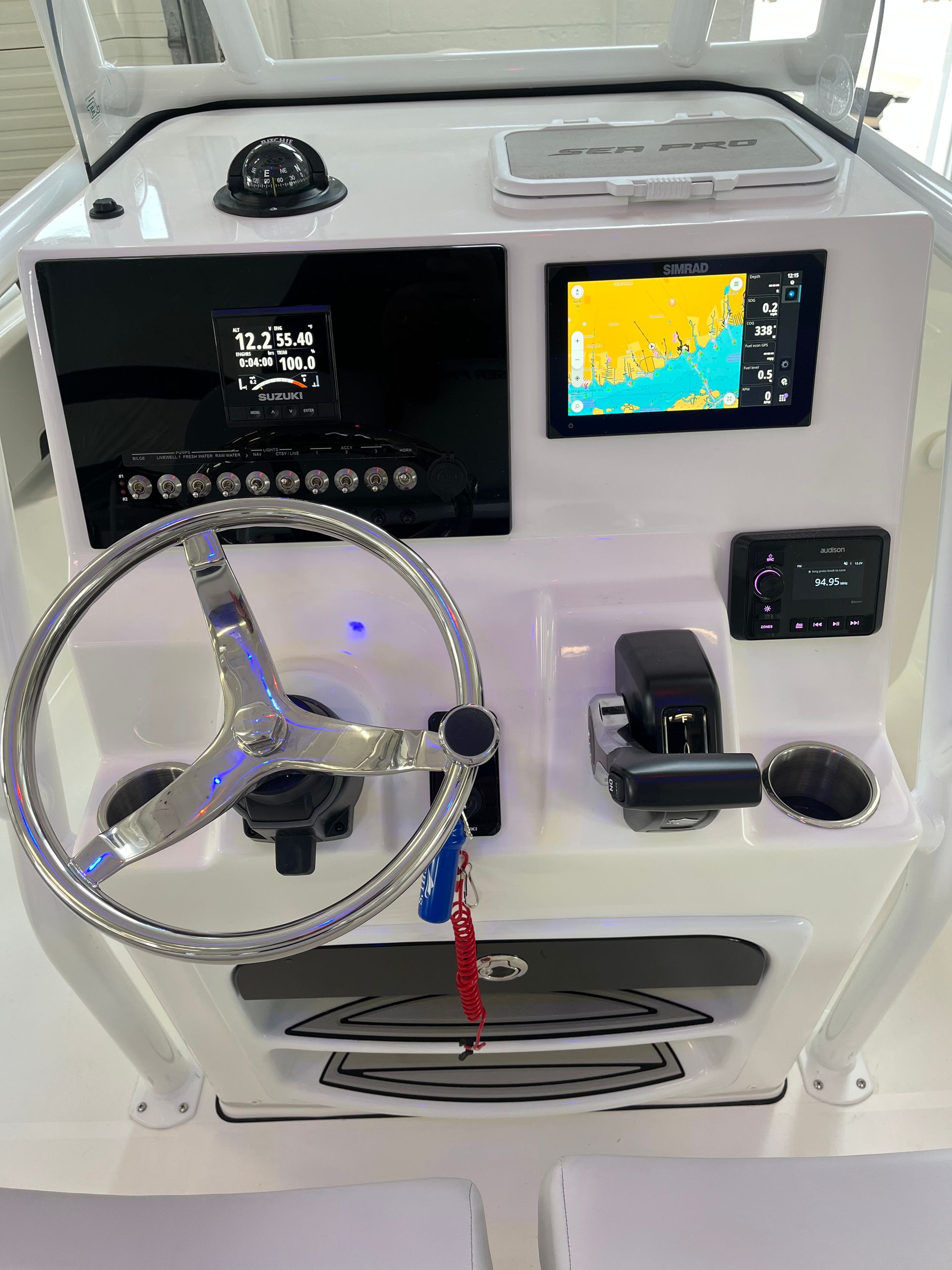 The cockpit of a boat with a steering wheel and a monitor.