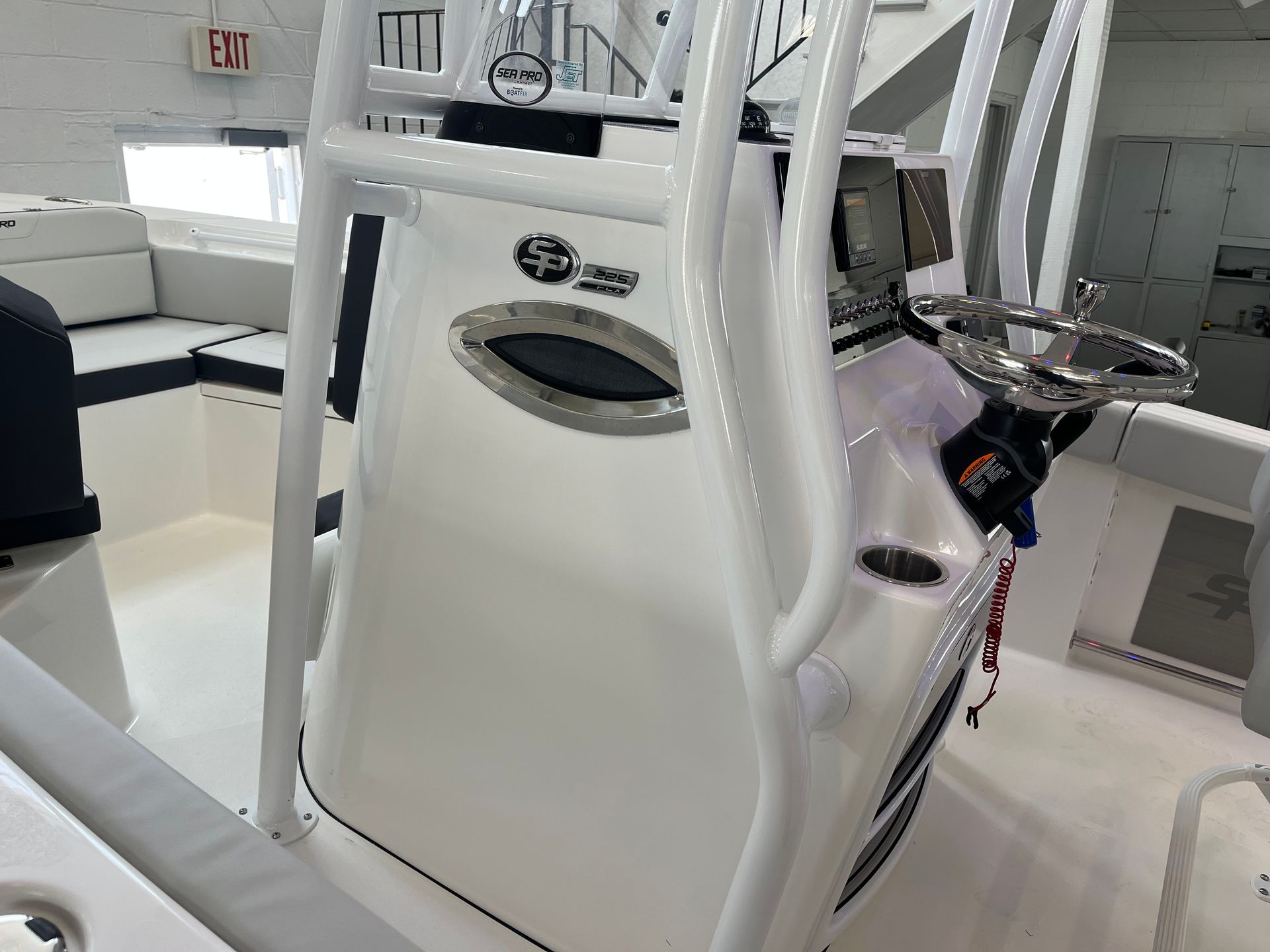 A white boat with a steering wheel and a ladder on the back of it.