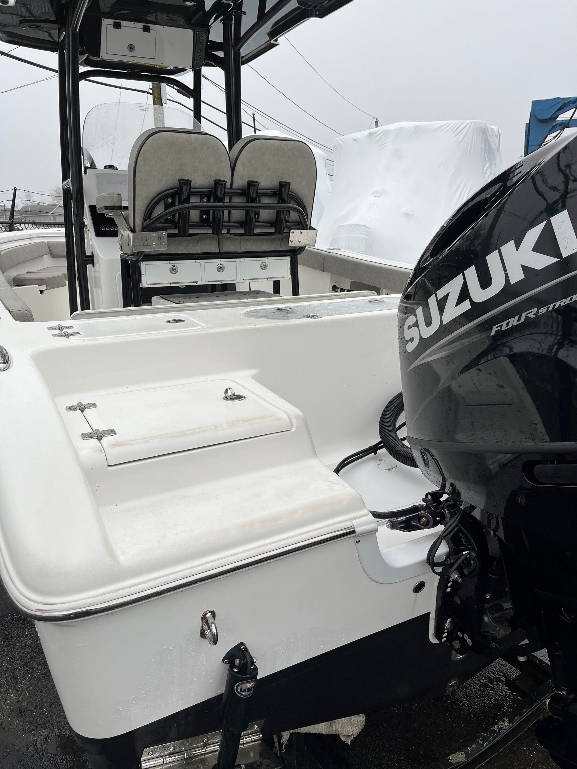 White boat with a Suzuki outboard motor, gray seats, and a closed storage hatch.