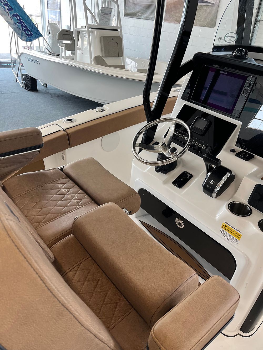 The cockpit of a boat with a steering wheel and a monitor.